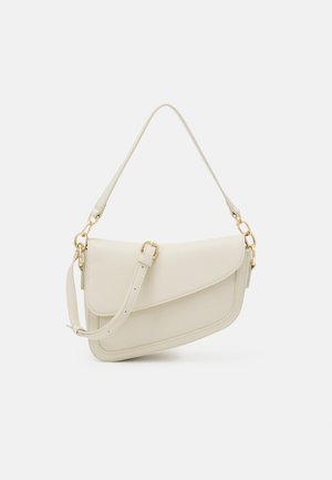 Crèmekleurige schoudertas van getextureerd leer met gouden beslag, een asymmetrische klep en een verstelbare band op een lichte achtergrond.