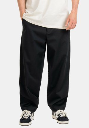 Schwarze, lässige Hose aus strapazierfähigem Stoff, mit seitlichen Taschen und geradem Bein design, kombiniert mit schwarz-weißen Sneakern.