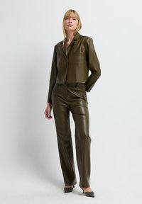 Braune Kunstleder-Bikerjacke mit einem einzelnen Taschen und passender, slim-fit Hose, beide mit einer glatten, glänzenden Textur.