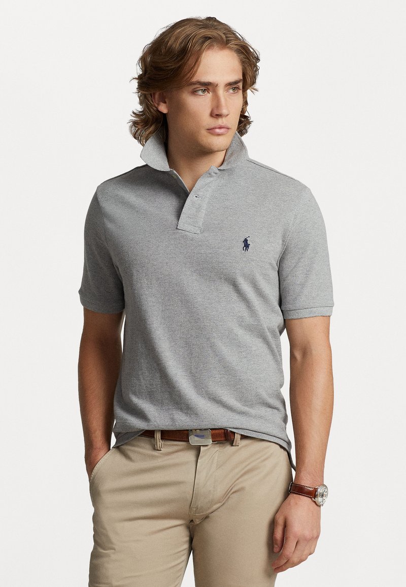 Gray polo shirt with a collared neck and short sleeves. Features a small navy logo on the chest and a textured fabric.