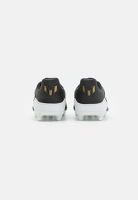 Scarpe da football in bianco e nero con texture liscia, dotate di dettagli dorati e un logo sul tallone. Tacchetti chiari e moldati alla base.