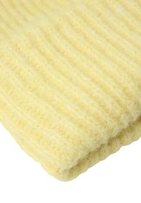 Szydełkowy żółty koc z miękką, teksturowaną powierzchnią i pionowym prążkowanym wzorem. Materiał wydaje się puszysty i ciepły, idealny do przytulnego użytku.