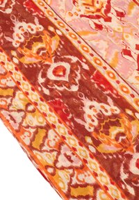 Tekstil med indviklede mønstre i røde, orange og gule nuancer, der har blomster- og geometriske designs på en blød, vævet stoftekstur.