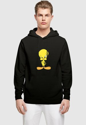 Svart hettegenser med et fronttrykk av en gul tegneseriefugl med store øyne og et uttrykksfullt positur. Stoffet ser glatt ut med en avslappet passform.