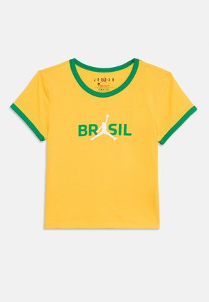 Sárga rövid ujjú póló zöld gallérral és mandzsettákkal, elöl középen "BRASIL" felirattal és fehér Jumpman logóval.