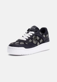 Black sneaker with white laces, featuring a textured upper with silver embellishments and a white rubber sole. Model branding on side.