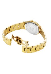 Reloj de pulsera de acero inoxidable dorado con una pulsera articulada, caja octagonal y esfera blanca con patrón. Cuenta con un cierre para asegurar el ajuste.