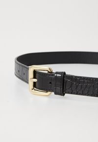 Cintura in pelle nera con una trama di coccodrillo, dotata di una fibbia in metallo dorato e fori di regolazione lungo la cinghia.