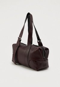 Mala de viagem em pele burgundy com fecho superior com zíper, alças pretas ajustáveis e acabamento texturizado. Forma redonda com design elegante.