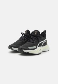 Schwarze Sportschuhe mit einer strukturierten Oberfläche, weißen Akzenten, einer hellgrünen Zwischensohle und einer kontrastierenden Gummisohle. Schnürdesign mit Logodetails.