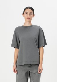 Grijze oversized t-shirt van zachte katoen met een ronde halslijn en korte mouwen; heeft een relaxte pasvorm en subtiele stikseldetails.