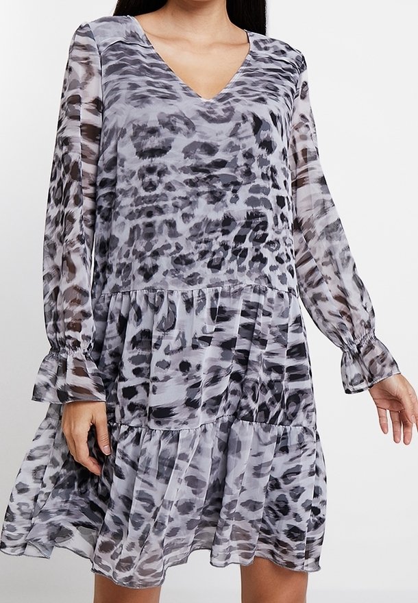 Robe grise transparente avec un décolleté en V, des manches longues et des volants superposés. Présente un motif imprimé animal noir et gris et des poignets froncés.