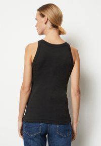 Top negru fără mâneci, cu guler rotund, ajustat și cu o margine ușor curbată. Fabricat din bumbac moale, fără modele sau embellishments vizibile.