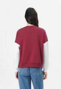 Bordeaux en grijs kleurgeblokte sweatshirt, ronde halslijn, ontspannen pasvorm, ribgebreide zoom en manchetten, zachte stof, zichtbare stikseldetails, casual stijl.