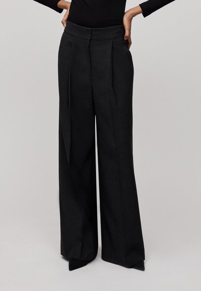 Pantalons noirs à jambes larges avec taille haute, présentant des plis, une texture lisse et une coupe précise pour un ajustement structuré.