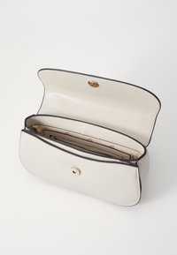 Cremefarvet lædertaske med en rund form, guldfarvet hardware og en lynlåslukning indeni. Foret med et mønstret stof. Åben og tom.