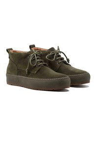 Bottines en suede vert olive avec un bout rond, semelle en caoutchouc plate et intérieure beige clair. Elles sont dotées de lacets ronds et d'un design de cheville mi-hauteur.