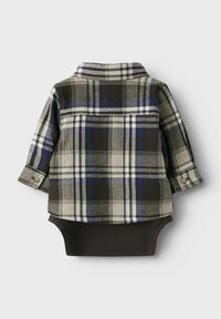 Camicia a maniche lunghe a quadri in grigio, nero e blu sopra un body nero, con colletto e dettagli ai polsini con bottone. Tessuto morbido.