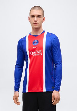 Jeune homme portant un maillot de football à manches longues bleu, rouge et blanc du Paris Saint-Germain avec le logo Qatar Airways.