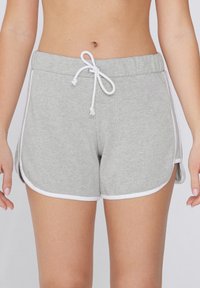Shorts en coton gris avec une taille élastique à cordon de serrage et un passepoil blanc. Les fentes latérales améliorent la mobilité. Texture douce avec une coupe décontractée.