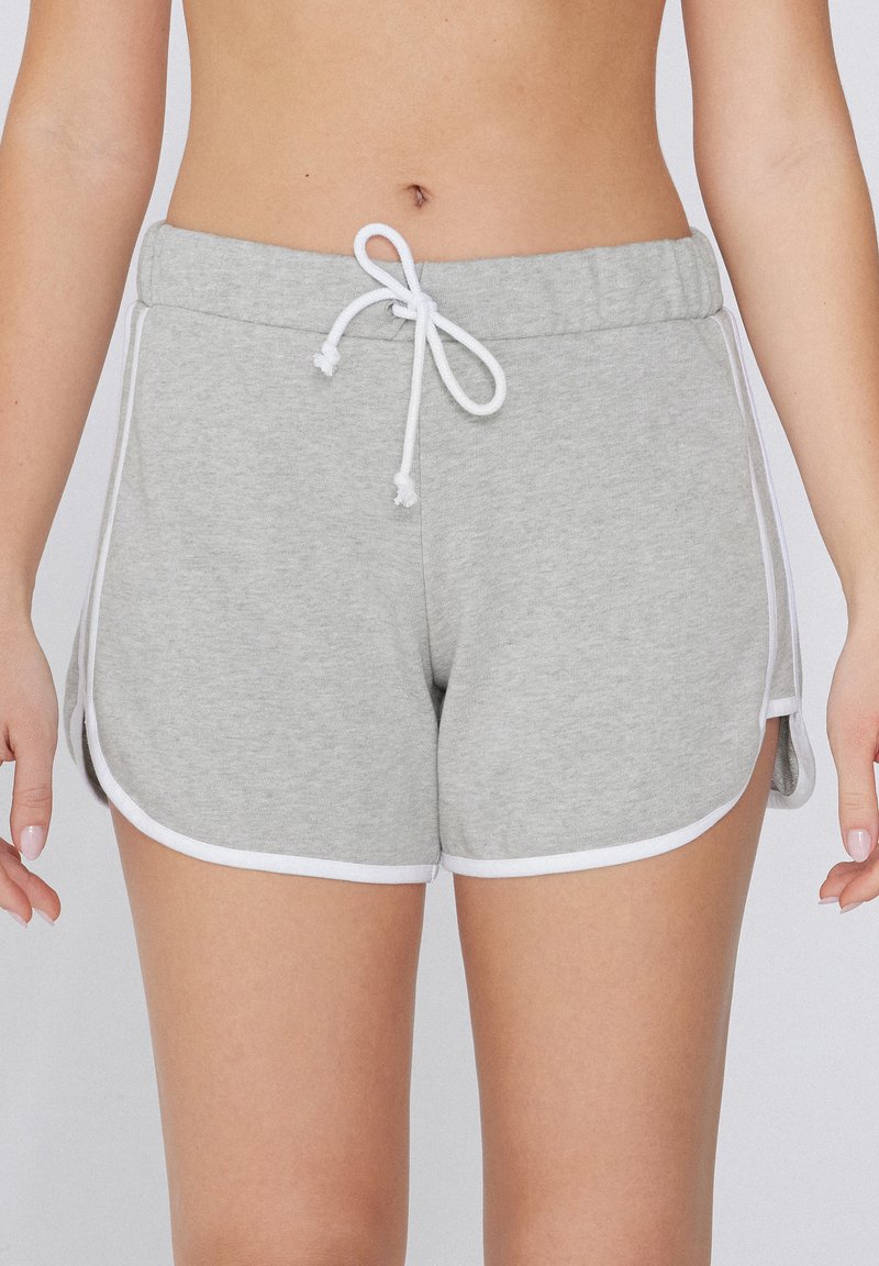 Shorts en coton gris avec une taille élastique à cordon de serrage et un passepoil blanc. Les fentes latérales améliorent la mobilité. Texture douce avec une coupe décontractée.