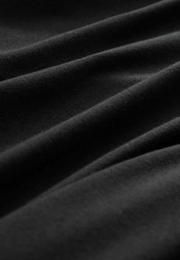 Tela negra con suaves ondas texturizadas y ligero brillo, que muestra una superficie lisa y sutiles variaciones de luz.