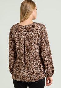 Blusa marrón y beige con manchas, confeccionada en tela suave, con escote redondo y mangas largas con puños elásticos.