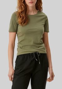 Oliven grøn kortærmet T-shirt lavet af blødt stof med rund halsudskæring, parret med sorte bukser med snøre og afslappet pasform.
