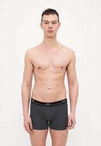 Dark gray boxer briefs with a black waistband featuring a logo. Soft, stretchy fabric with a fitted design. No visible patterns or accents.