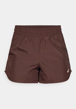 Pantaloni sportivi marroni con una texture a coste, vita elastica e un piccolo logo in un colore chiaro sulla parte anteriore inferiore.