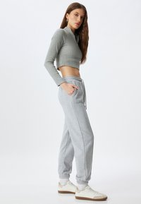 Grijze cropped lange mouw top met een kleine nek rits, gecombineerd met lichtgrijze sweatpants met zijzakken en elastische boorden.