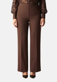 Pantaloni marroni a gamba larga realizzati in tessuto liscio; caratterizzati da vita alta e vestibilità sartoriale, abbinati a décolleté nere in vernice.