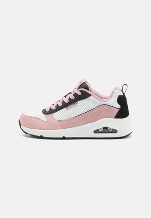 Athletic shoe with a mix of white mesh and pink suede, black accents, rounded toe, lace-up design, and visible air cushioning in the sole.
