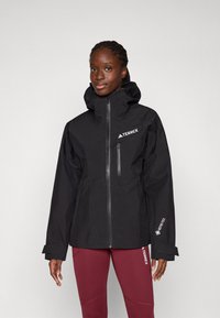 Schwarze wasserdichte Jacke mit hohem Kragen, Frontreißverschluss und Logo-Akzenten. Verfügt über ein elegantes Design und verstellbare Bündchen für mehr Komfort.
