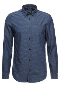 Mörkblå långärmad skjorta med små vita prickar, krage med knappar och en bröstficka. Tillverkad av ett strukturerat tyg.