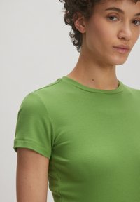 Geribbelde groene T-shirt met korte mouwen en een ronde hals, met een zachte textuur en een getailleerde pasvorm.