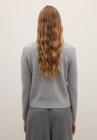 Women's gray knit sweater with long sleeves and ribbed hem, made of soft material. Features a classic design and a relaxed fit.