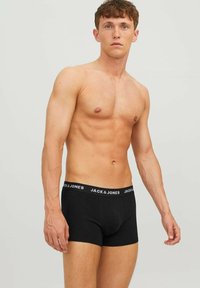 Schwarze Baumwoll-Boxershorts mit einer engen Passform, ausgestattet mit einem kontrastierenden weißen Logo-Bund an der Taille, glatter Textur und einer Länge bis zur Mitte des Oberschenkels.