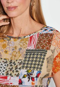 Mehrfarbiges Oberteil mit einem Patchwork-Design, das florale, geometrische und abstrakte Muster in verschiedenen Texturen und Farbtönen zeigt, Rundhalsausschnitt.