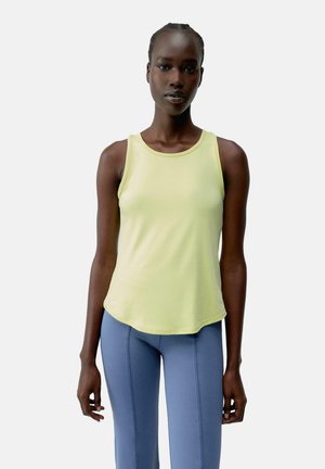 Lys gul tanktop med rund hals og uten ermer, kombinert med blå, tettsittende bukser med sømdetaljer. Jevn tekstur.