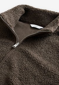 Bruine fleece pullover met een hoge kraag, voorzien van een rits en een zachte, gestructureerde oppervlakte. Etiket afgebeeld: "NEXT."