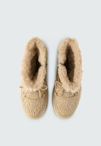 Tannfarbene Stiefel mit einem flauschigen, weichen Innenfutter, strukturierter Stoffaußenseite und Schnürsenkeln. Runde Zehenpartie und eine strukturierte Gummisohle für gute Griffigkeit.
