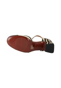 Scarpa con tacco alto con tomaia nera e beige a motivo, dotata di una cinghia e una suola in gomma testurizzata, che mette in risalto una finitura lucida.