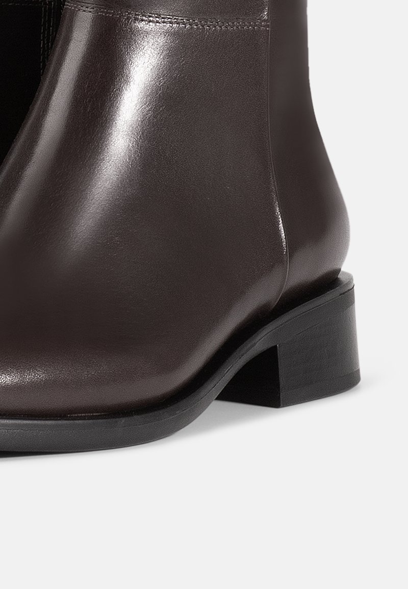 Brown leather ankle boot with a smooth finish, low block heel, and rounded toe. Features subtle stitching along the seams for detail.