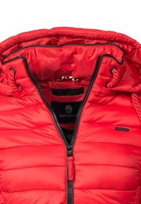 Röd pufferjacka med fodrad huva, svart dragkedja, ribbade detaljer och en logotagg. Strukturerad, quiltad yta för isolering.