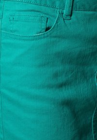 Shorts en denim turquoise avec un design élégant, poche avant et tissu texturé avec des détails de couture visibles.