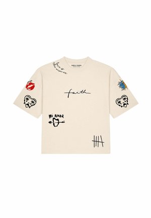 Femme portant un t-shirt blanc oversize avec des imprimés noirs et rouges incluant un cœur qui pleure et des marques de comptage, et des lunettes de soleil noires.