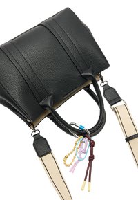 Czarna torebka skórzana o fakturze z podwójnymi uchwytami i odczepianym paskiem na ramię. Udekorowana kolorowymi zawieszkami i elementami metalowymi.
