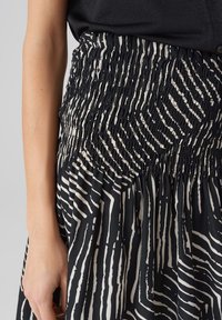 Hame patterned mustavalkoinen, jossa on smockattu vyötärö, pystysuorat viivat, pehmeä kankaan rakenne ja virtaava muotoilu.