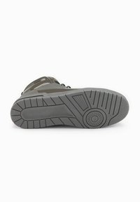 Calzado gris con una suela de goma texturizada que presenta profundas estrías y un acento circular, diseñado para ofrecer tracción y estabilidad.